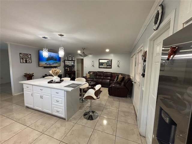 kitchen featuring pendant lighting, a breakfast bar, crown molding, a kitchen island, and white cabinetry