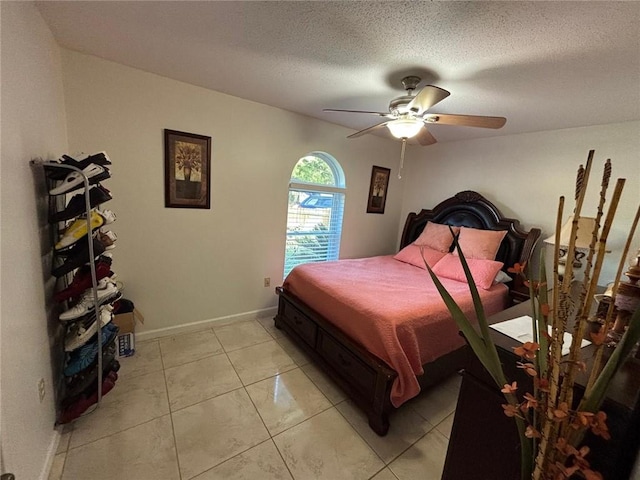 bedroom with ceiling fan, light tile patterned floors, and a textured ceiling