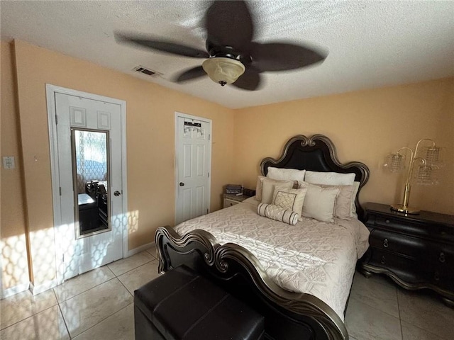 tiled bedroom with a textured ceiling and ceiling fan