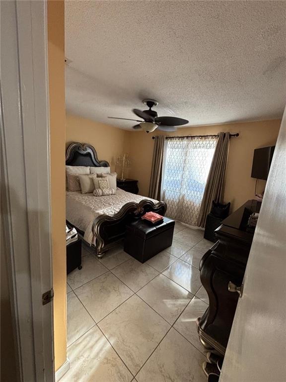 bedroom featuring light tile patterned floors, a textured ceiling, and ceiling fan