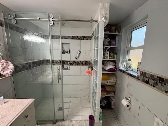 bathroom featuring walk in shower, vanity, and tile walls