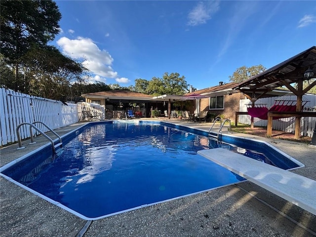 view of swimming pool with a diving board and a patio