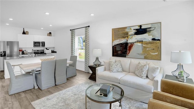 living area featuring light wood-style floors, recessed lighting, and baseboards