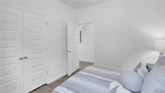 bedroom with wood finished floors, a closet, and baseboards