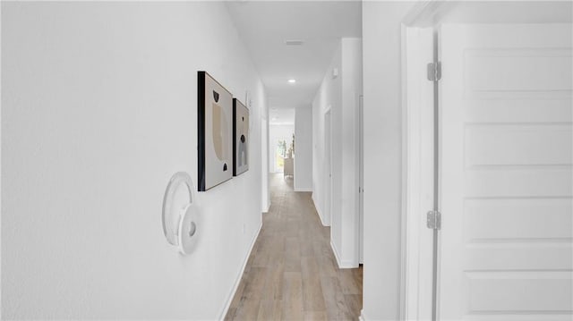 hall with light wood-type flooring, baseboards, and recessed lighting