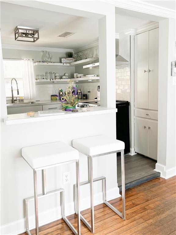 bar featuring tasteful backsplash, wood finished floors, visible vents, and a sink