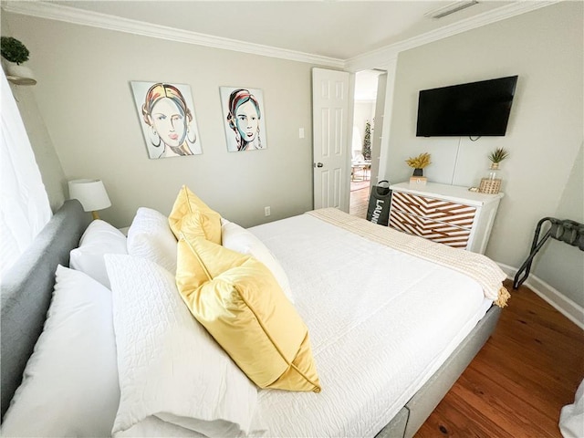 bedroom featuring visible vents, ornamental molding, baseboards, and wood finished floors