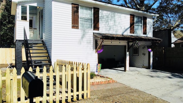 view of front of home with an attached garage, concrete driveway, and fence