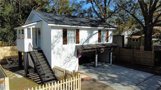 exterior space featuring stairway, concrete driveway, a garage, and fence