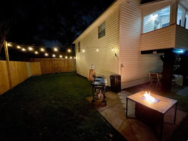 back of house at twilight with a patio, a yard, a fire pit, and fence private yard