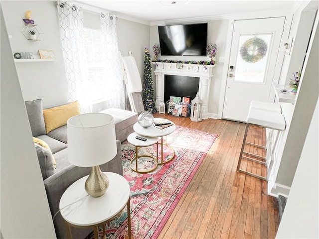 living area with a healthy amount of sunlight, baseboards, wood-type flooring, and ornamental molding