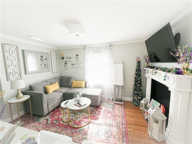 living room with baseboards, light wood-style flooring, a fireplace, and ornamental molding