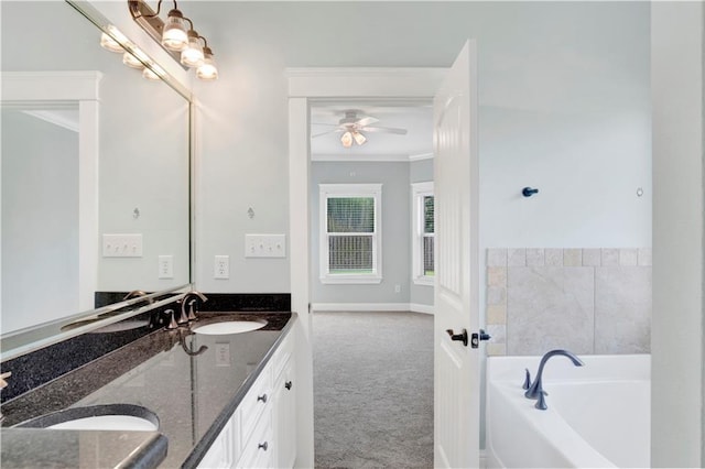 bathroom with ceiling fan, ornamental molding, vanity, and a bathing tub