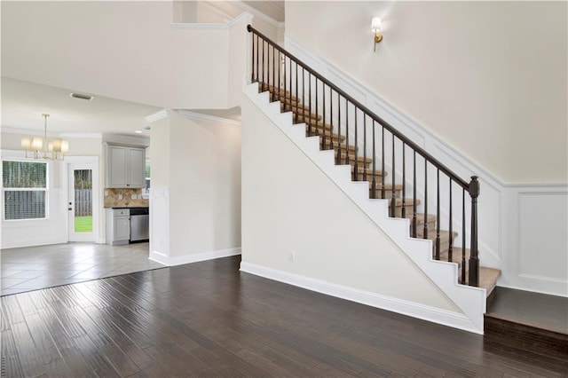 stairway with crown molding, an inviting chandelier, and hardwood / wood-style floors