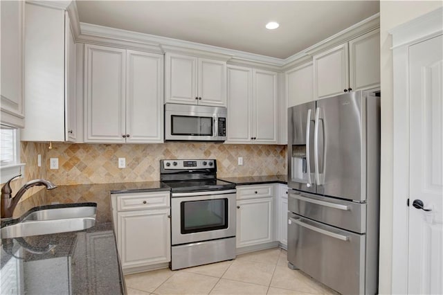 kitchen featuring dark stone countertops, sink, light tile patterned floors, and appliances with stainless steel finishes