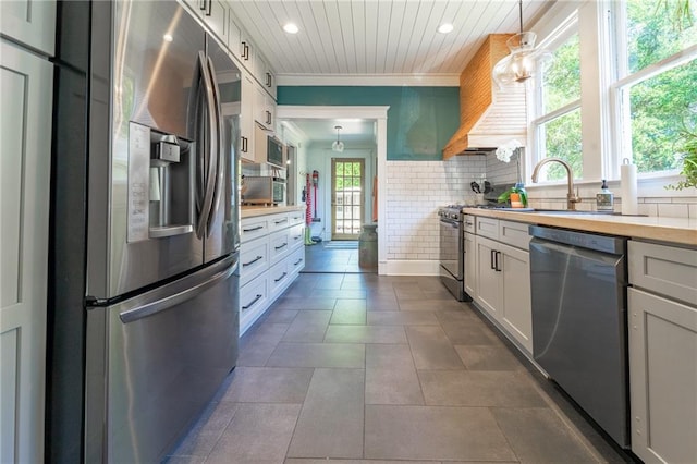 kitchen featuring appliances with stainless steel finishes, decorative light fixtures, dark tile patterned floors, white cabinetry, and tasteful backsplash