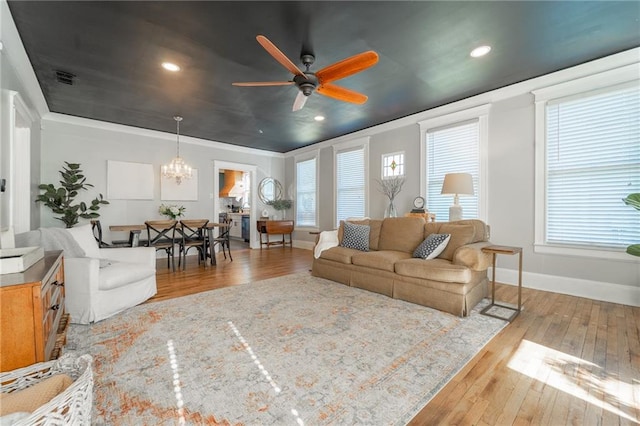 living room featuring ceiling fan with notable chandelier, light hardwood / wood-style flooring, and ornamental molding