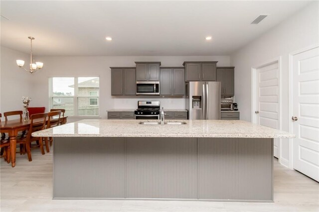 12927 Sanderling Loop, Daphne, AL 36527 - kitchen with appliances with stainless steel finishes, gray cabinetry, a chandelier, a center island with sink, and light stone counters