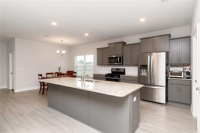 12927 Sanderling Loop, Daphne, AL 36527 - kitchen with stainless steel appliances, light wood-style floors, light stone counters, an island with sink, and gray cabinetry
