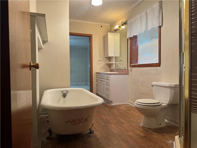 bathroom featuring wood-type flooring, toilet, vanity, crown molding, and a bathtub