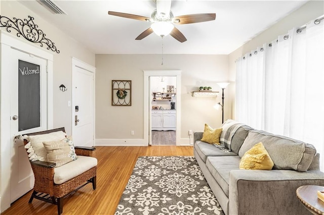 living area with a ceiling fan, light wood-style floors, and baseboards