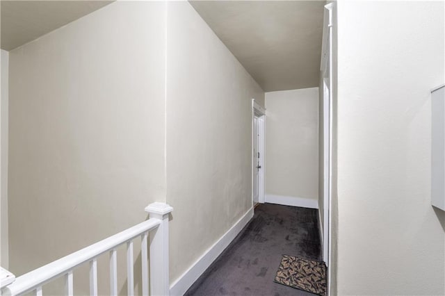 hall featuring carpet flooring, an upstairs landing, and baseboards