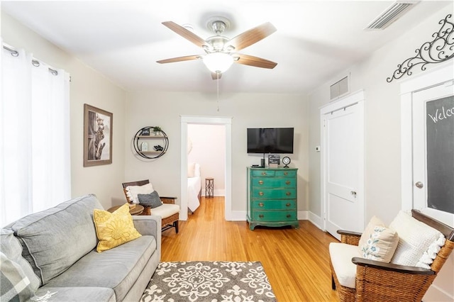 living room with light wood finished floors, a ceiling fan, and baseboards