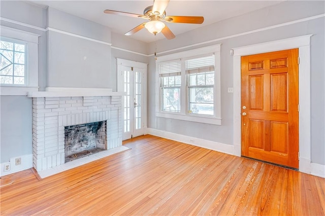 unfurnished living room with a brick fireplace, ceiling fan, and light wood-type flooring