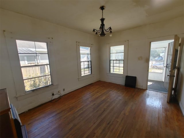 unfurnished dining area with a chandelier and dark hardwood / wood-style flooring