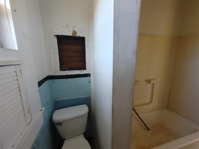 bathroom featuring tile walls, a bathing tub, and toilet