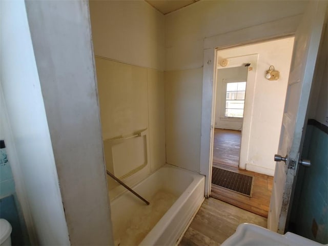 bathroom with a tub to relax in and wood-type flooring