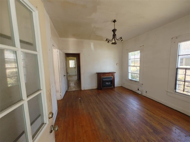 unfurnished living room with dark wood-type flooring, a fireplace, and a chandelier