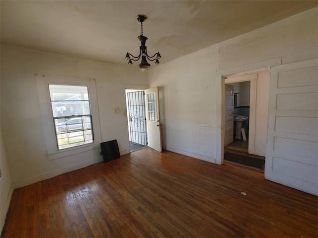 unfurnished dining area featuring dark wood-type flooring and a notable chandelier