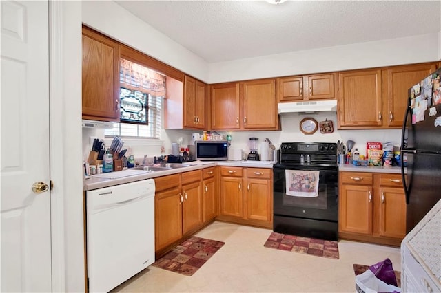 kitchen featuring under cabinet range hood, brown cabinets, black appliances, and light countertops