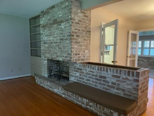 unfurnished living room with a brick fireplace, hardwood / wood-style flooring, and built in features