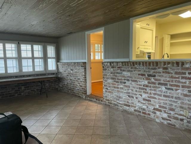 tiled living room with brick wall and wood ceiling