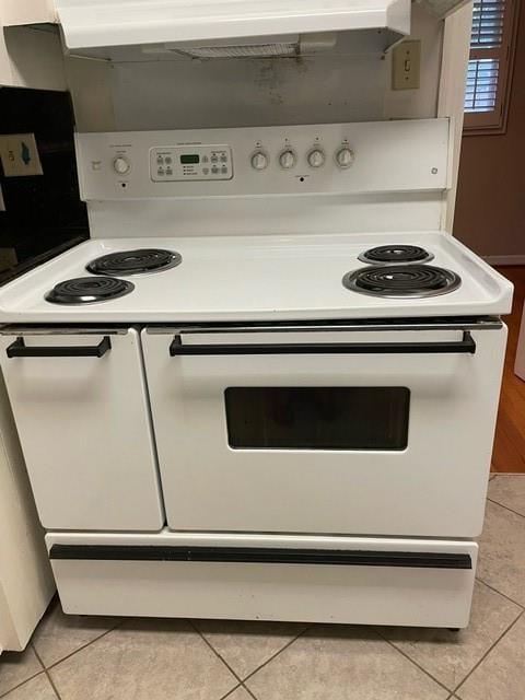 kitchen featuring range with two ovens, light tile patterned floors, and white cabinets