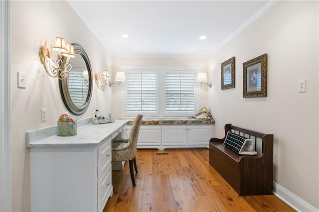 office area with built in desk, ornamental molding, and light hardwood / wood-style flooring