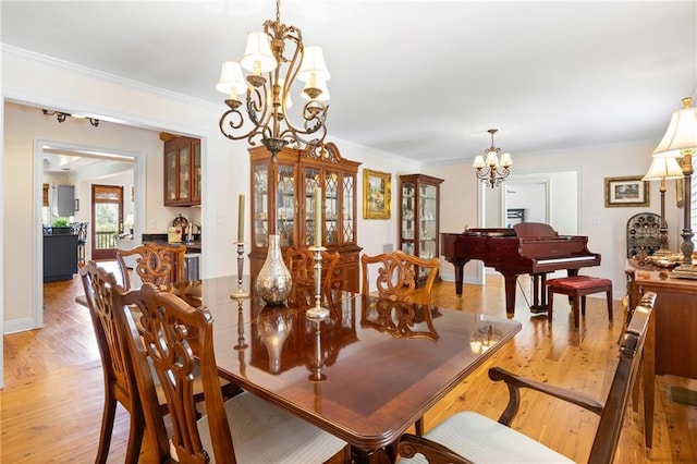 dining room with a notable chandelier, light wood-type flooring, and crown molding