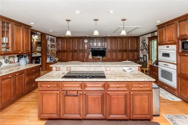 2100 River Forest Rd, Mobile, AL 36605 - kitchen with black electric cooktop, a kitchen island, double oven, light wood-style flooring, and brown cabinetry