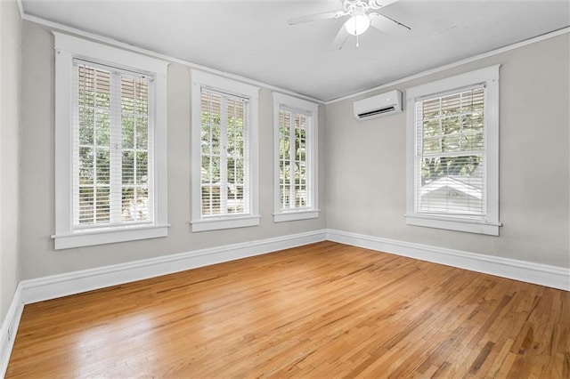 unfurnished room with wood-type flooring, an AC wall unit, and a wealth of natural light