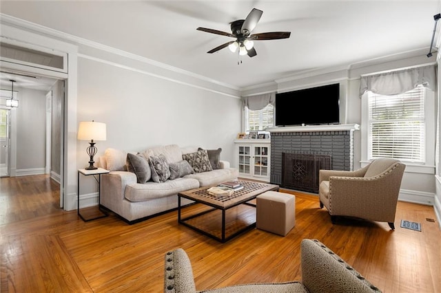 living room with ceiling fan, ornamental molding, and a fireplace