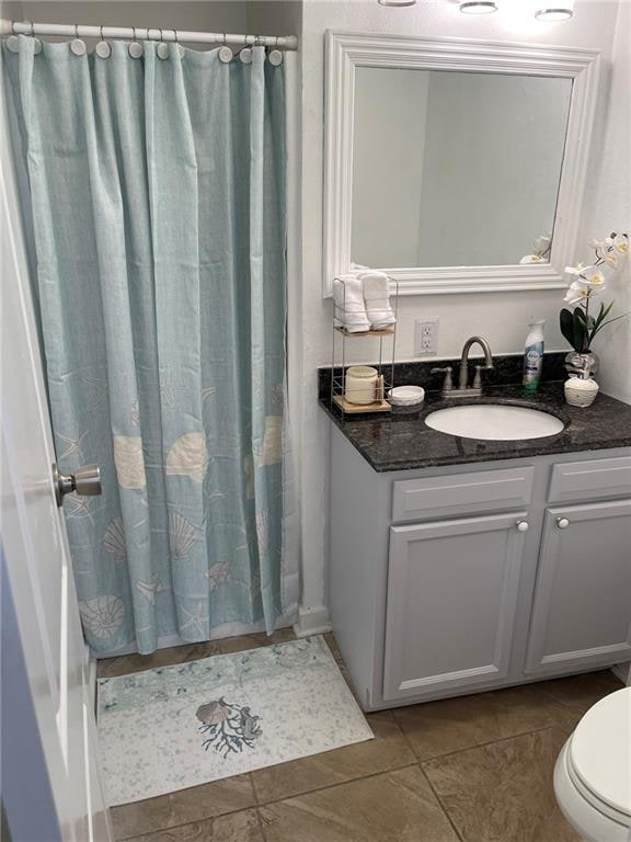 bathroom featuring walk in shower, vanity, toilet, and tile patterned floors