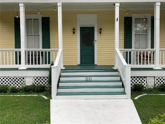 entrance to property featuring a lawn and covered porch