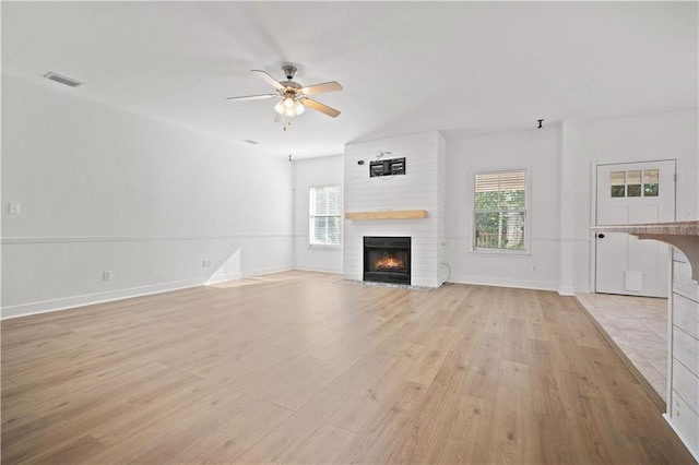 unfurnished living room with ceiling fan, light wood-type flooring, and a fireplace