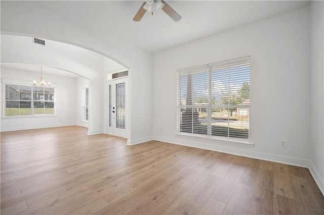 interior space with ceiling fan with notable chandelier and light wood-type flooring