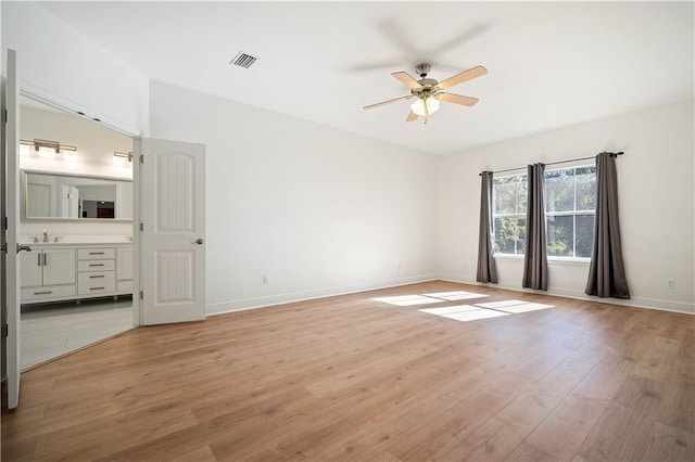 unfurnished bedroom featuring sink, ensuite bathroom, light hardwood / wood-style floors, and ceiling fan