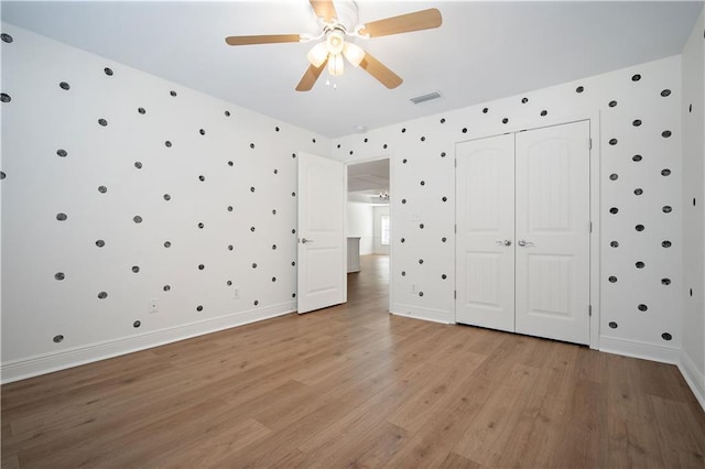 unfurnished bedroom featuring light hardwood / wood-style floors, a closet, and ceiling fan