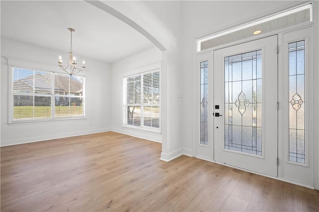 entrance foyer featuring a healthy amount of sunlight, a notable chandelier, and light wood-type flooring