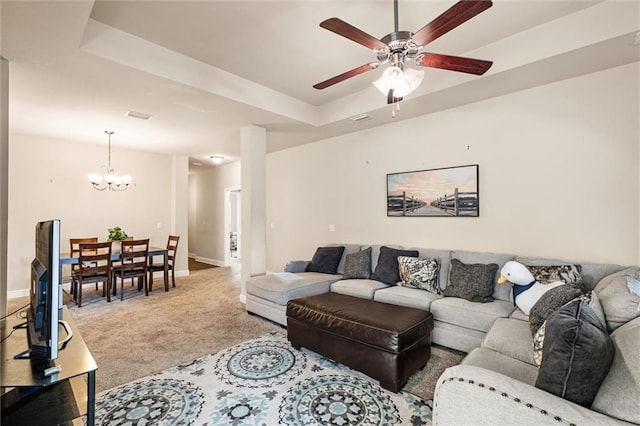 carpeted living room featuring a raised ceiling and ceiling fan with notable chandelier